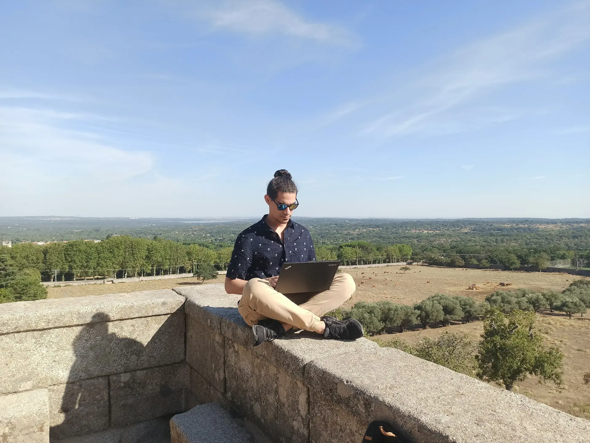 jeune homme travaillant sur laptop en hauteur avec vue panoramique sur paysage rural