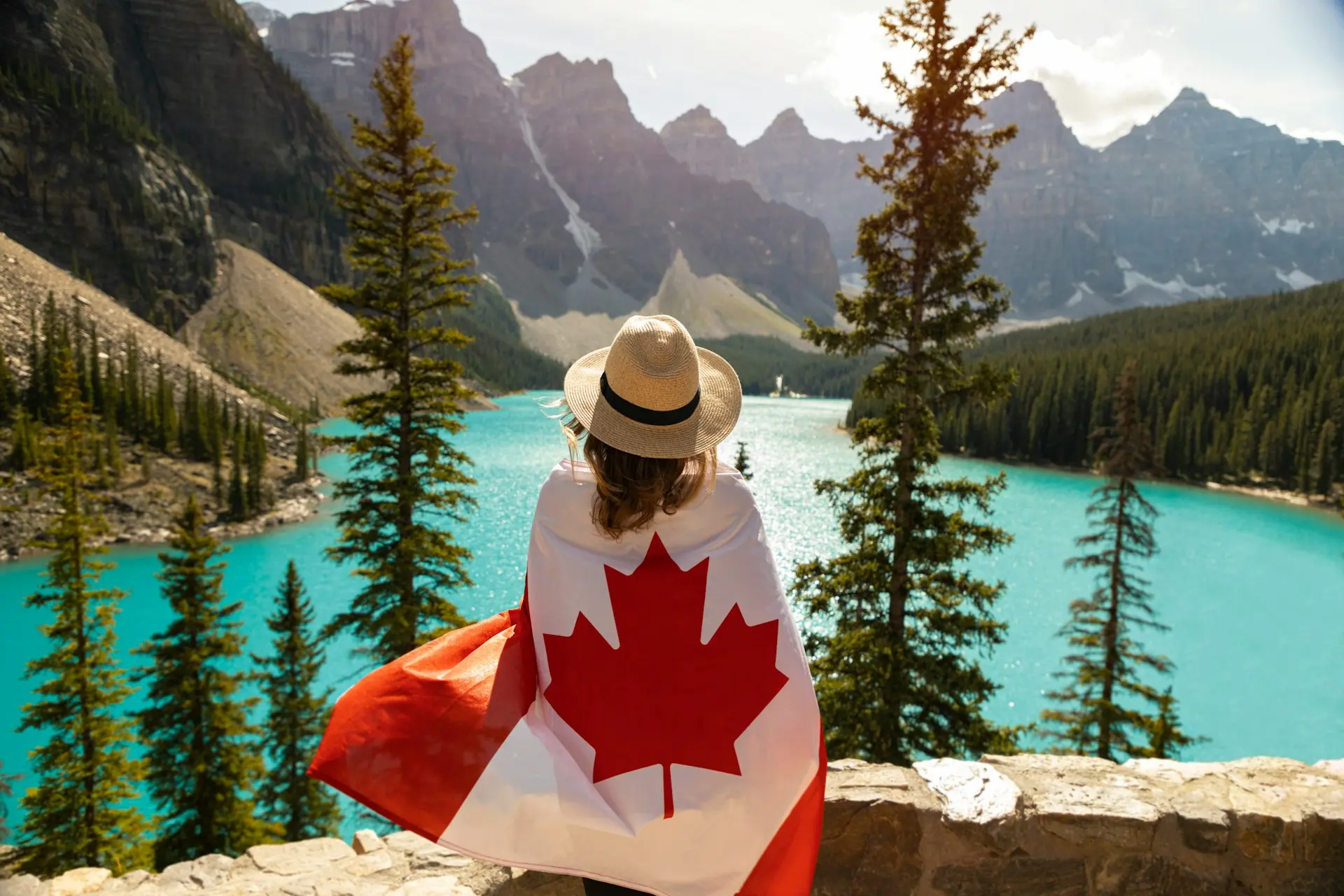 femme avec drapeau canadien face au lac turquoise des Rocheuses